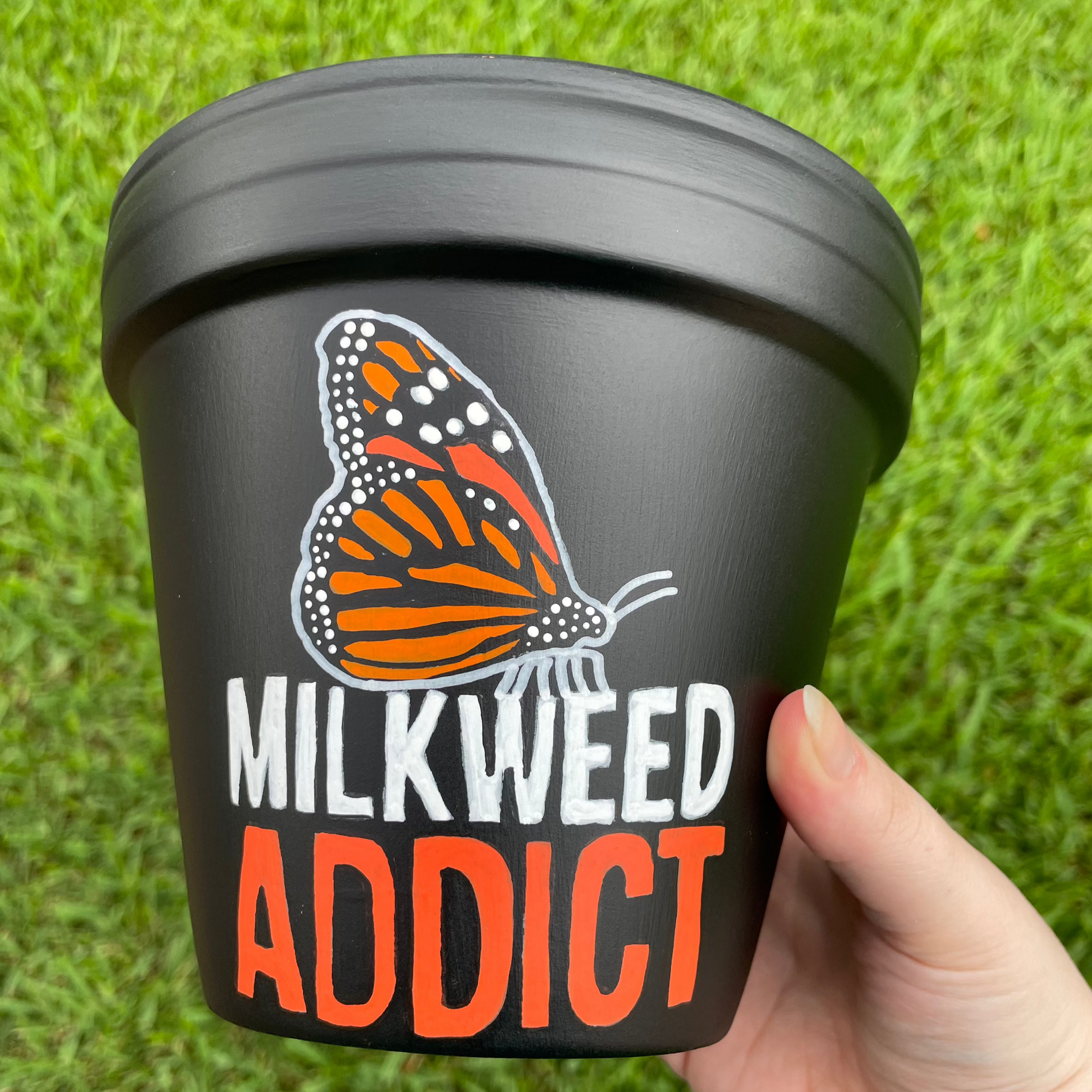 Hand-painted terracotta pot showcasing a monarch butterfly and 'Milkweed Addict' text.