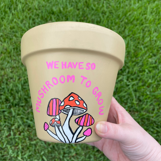 Hand-painted terracotta pot featuring a whimsical mushroom design wrapping around 180 degrees.